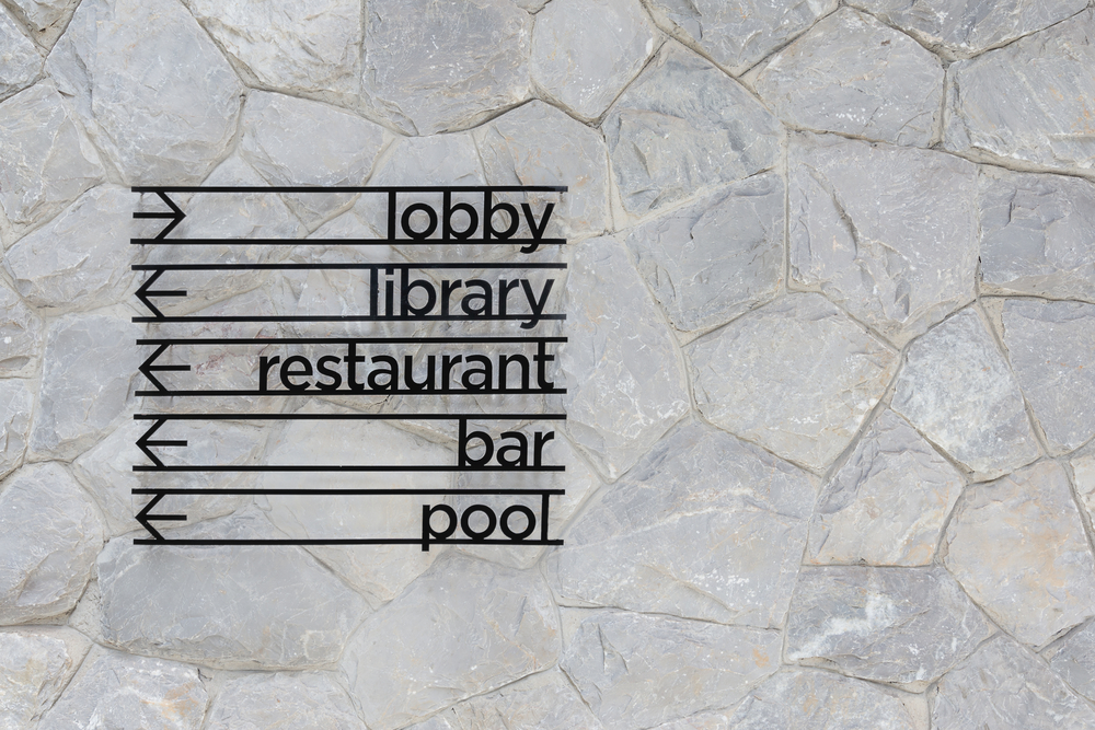 Hotel,Arrow,Signage,On,Stone,Wall,Background.,Lobby,,Library,,Restaurant,